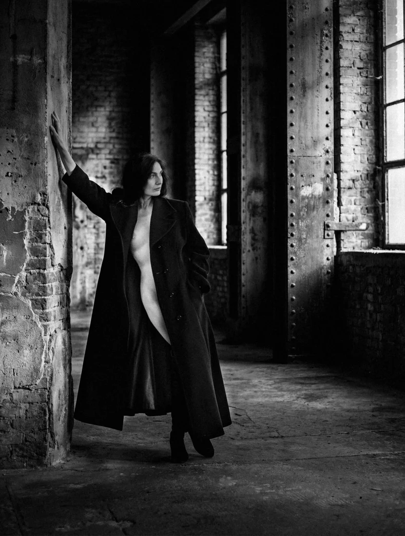 Full-length portrait in a long coat in an industrial interior